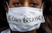 Met de tekst „Ik kan niet ademen” demonstreert een vrouw tegen het politiegeweld in Amerika waarbij George Floyd omkwam. beeld ANP, Remko de Waal