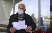 Andreas Christodoulou (92) uit Cyprus toont zijn Covid-19-vaccinatiebewijs. Hij ontving die direct na de prik. beeld EPA, Katia Christodoulou