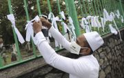 Een Sri Lankaanse moslim bindt een wit lint aan een hek op een begraafplaats tijdens een protest tegen gedwongen crematie van Covid-19-slachtoffers in Colombo, Sri Lanka. beeld EPA, Chamila Karunarathne