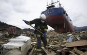 Een Japanse brandweerman zoekt naar overlevenden na de verwoestende aardbeving ​en tsunami die het land  op 11 maart 2011 troffen. beeld AFP, Fred Dufour