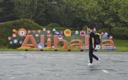 Een man loopt richting het hoofdkantoor van de Chinese e-commercegigant Alibaba in Hangzhou. Het enorme logo van het bedrijf op de achrgrond dient hier als wegwijzer richting het gebouw.​  beeld AFP, Kelly Wang