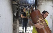Israëliërs redden woensdagmorgen Torarollen uit een verbrande synagoge in Lod. beeld EPA, Abir Sultan