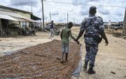 Twee politieagenten arresteren een kind op een cacaoplantage in Ivoorkust. Dit gebeurde vorige maand in het kader de operatie tegen kinderarbeid ”Nawa 2”. Zaterdag is het de internationale dag tegen kinderarbeid. beeld AFP, Sia Kambou
