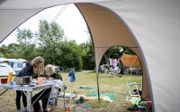 Jonge kampeerders vermaken zich bij hun tent op een natuurcamping van Staatsbosbeheer op Terschelling. beeld ANP, Sem van der Wal