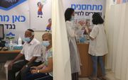 In Israël kunnen zestigers al om een derde dosis van het Pfizervaccin. Op de foto: een Israëlisch stel wacht op de derde prik bij de Clalit Health Service in Jeruzalem op 1 augustus 2021.  beeld AFP, Menahem Kahana
