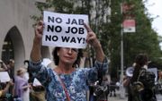 Een groep betogers protesteert bij het Prebyterian Hospital in New York tegen verplichte vaccinatie voor medewerkers in de zorg.  beeld AFP, Spencer Platt