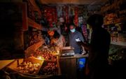 Een verkoper in Colombo verlicht zijn winkel met kaarslicht. Elektriciteit is dagelijks meerdere uren afgesloten. beeld EPA, Chamila Karunarathne