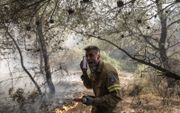Brandweerman Panagiotis Haratsis, 35, opereert tijdens een bosbrand in de noordoostelijke buitenwijk van Pallini, nabij Athene, Griekenland. beeld EPA, Kostas Tsironis