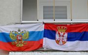 Een Russische en een Servische vlag hangen op een balkon bij een nieuwe wegversperring die is opgezet in de verdeelde  Kosovaarse stad Mitrovica. beeld AFP, Armend NIMANI