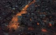 Luchtopname van een verlichte hoofdweg en donkere straten in de Turkse plaats Kahramanmaras, een maand na de zware aardbeving in het zuidoosten van Turkije. beeld AFP, Eylul YASAR