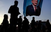 Mensen lopen onder een spandoek waarop presidentskandidaat Kemal Kilicdaroglu staat. beeld EPA, Sedat Suna