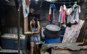 Een moeder kookt eten voor haar gezin in Manilla, de hoofdstad van de Filipijnen. beeld EPA, Rolex Dela Pena