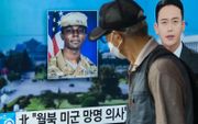 Een man loopt woensdag in de Zuid-Koreaanse hoofdstad Seoul langs een televisie waarop tijdens een uitzending een foto wordt getoond van Travis King. De Amerikaanse militair liep over naar Noord-Korea tijdens een tour. beeld AFP, Anthony Wallace