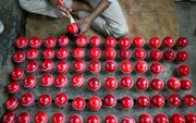 Een arbeider polijst cricketballen in een werkplaats in Meerut, India. beeld AFP, Money Sharma