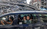 Palestijnen rijden door verwoestingen als gevolg van Israëlische luchtaanvallen in Rafah, in de Gazastrook. beeld AFP, Said Khatib