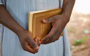 Bijbel of Koran? Om moslims in het dorp Tabalo I (Togo) geen aanstoot te geven, moest  evangelist  Fatiou zijn Bijbel verpakken in kaftpapier met Arabische letters erop.  beeld Jaco Klamer