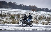 Fietsers in een winters landschap op de Tankenberg tussen Oldenzaal en De Lutte. Het KNMI gaf woensdag code geel vanwege gladheid door winterse buien, met hagel en sneeuw. beeld ANP, Vincent Jannink