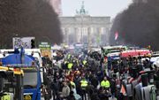 Trekkers en vrachtwagens staan maandag bij de Brandenburger Tor in Berlijn. Boeren, truckers en andere ontevreden Duitsers demonstreren tegen het regeringsbeleid. beeld AFP, John Macdougall