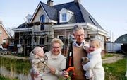 Theo en Jenny van der Linden met twee kleinkinderen voor hun nieuwbouwhuis in Brakel. „Veel dorpelingen houden de bouw in de gaten”, zegt Jenny. beeld Cor de Kock