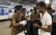 Politieagenten controleren vrijdag de bagage van treinreizgers op het station van de Srilankaanse hoofdstad Colombo. beeld EPA,  Pushpa Kumara