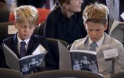 De 10-jarige tweelingbroers Will (l.) en Charlie Balsley zijn verdiept in het programmaboekje van de Days of Remembrance.  beeld EPA, Erik S. Lesser
