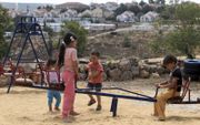 In vergelijking met buurlanden is de verhouding tussen moslims en christenen in de Palestijnse gebieden beter. Foto: Palestijnse kinderen spelen in een speeltuin in een dorp op de Westoever, met een Israëlische nederzetting op de achtergrond. beeld AFP, J