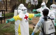 Leden van het Team voor Veilige en Waardige Begrafenissen (SDB) van het Rode Kruis bereiden zich voor op hun werk na het overlijden van een ebolapatiënt in Beni, Congo, begin juni. beeld EPA, Maria Santto