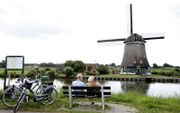 Fietsers rusten langs de Ringvaart van De Beemster. Fietsen en molens worden door veel Nederlanders gezien als typerend voor de Nederlandse identiteit. beeld ANP, Koen Suyk