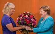 De Duitse bondskanselier Angela Merkel was vorige week woensdag jarig en kreeg daarom tijdens de ministerraad bloemen van minister van Justitie Christine Lambrecht. beeld AFP, John MacDougall