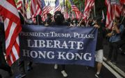 Steeds meer jonge Hongkongers zwaaien met Amerikaanse vlaggen en dragen spandoeken mee met teksten als ”President Trump, please liberate Hong Kong”. beeld AFP, Vivek Prakash