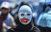 Een demonstrant draagt tijdens een betoging in Istanbul een masker met de vlag van Oost-Turkestan die door Oeigoeren wordt gebruikt. beeld AFP, Ozan Kose
