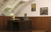 Stalin kijkt toe van achter een bureau.   beeld Floris Akkerman