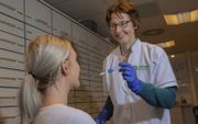 Linda Nederhoed maakt voor de DNA-test met een wattenstaafje een uitstrijkje van het wangslijmvlies.  beeld Rob Voss