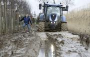 Tot de assen weggezakt ploegt een zware tractor van Betuwe Boomkwekerij uit Opheusden door de modder. De zeldzaam grote wateroverlast maakt aan alle droogteverhalen definitief een eind. beeld VidiPhoto