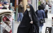 Een Iraanse vrouw draagt een gezichtsmasker en beschermende handschoenen tijdens het winkelen op de grote bazaar in Teheran. beeld EPA, Abedin Taherkenareh