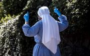 Een non draagt een mondkapje en handschoenen terwijl ze vrijdag over straat loopt in het Italiaanse dorpje Grottaferrata, ten zuidoosten van Rome. beeld EPA, Angelo Carconi