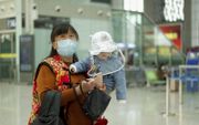 Een Chinese moeder met haar kindje op een treinstation aan de rand van de zwaar getroffen provincie Hubei.​ China heft de meeste beperkingen voor burgers in die regio weer op nu het coronavirus onder controle lijkt. beeld AFP, Noel Celis