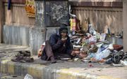 Een dakloze man eet voedselresten op straat tijdens de lockdown in de Indiase stad Ahmedabad. beeld AFP, Sam Panthaky