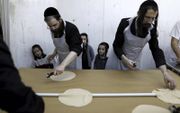 Foto van Pesach (Pasen) vorig jaar: Ultraorthodoxe Joden zijn bezig met de voorbereiding van –ongezuurde– matzes in een bakkerij in de Israëlische stad Bnei Brak. beeld AFP, Menahem Kahana