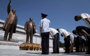 Mensen betuigen hun respect voor bronzen beelden van wijlen leiders Kim Il Sung (l.) en Kim Jong Il. Noord-Koreaanse leiders worden als goden vereerd. Het christendom is verboden in het land. beeld AFP, Andrew Harnik