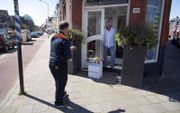 Een postbezorger doet een contactloze bezorging in Haarlem. Bij PostNL is het deze dagen aanzienlijk drukker dan voor de coronacrisis. beeld ANP, Olaf Kraak