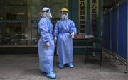Medisch personeel in Wuhan wacht reizigers op om hen te testen op besmetting met het coronavirus. Ook al is de lockdown daar grotendeels voorbij, de vrees voor een nieuwe uitbraak leidt tot aanhoudende checks en controles.  beeld AFP, Hector Retamal