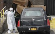 Een begrafenisondernemer in New York trekt beschermende kleding aan. beeld AFP, Bryan R. Smith