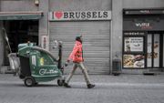 Een schoonmaker passeert gesloten winkels in Brussel. Het is rustig in de stad nu de instellingen van de Europese Unie zovele mogelijk via digitale kanalen bijeenkomen. De Europese regeringsleiders vergaderen donderdag online over een herstelplan voor de 