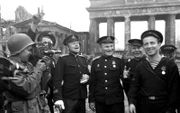 Een Amerikaan filmt Russische militairen voor de Brandenburger Tor in Berlijn, mei 1945. beeld AFP