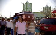 Mannen dragen een kist met lichaam van priester Ivan Anorve. Hij werd in 2018 doodgeschoten door een bende, vermoedelijk vanwege zijn kerkelijke werk. beeld AFP, Francisco Robles