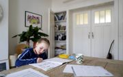 In de praktijk werd het schoolwerk vooral ’s morgens gedaan. Foto: een 8-jarige leerling werkt thuis in Den Haag. beeld ANP, Bart Maat