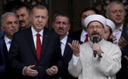De Turkse president Erdogan (l.) bidt tijdens de opening van een nieuwe moskee in Istanbul. Het islamistische beleid van de president zorgt ervoor dat steeds meer Turkse jongeren zich juist afkeren van de islam, betoogt opiniemaker Mustafa Akyol. beeld Re