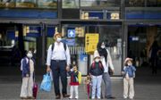 In Rotterdam en omstreken stijgt het aantal coronabesmettingen opnieuw. Op de foto: Een gezin met mondkapjes op voor het Centraal Station in de havenstad. beeld ANP, Jerry Lampen