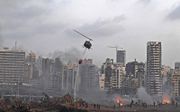 Een helikopter probeert meerdere branden te blussen op de plaats van de enorme explosie die dinsdag het hart van de Libanese hoofdstad trof. beeld AFP